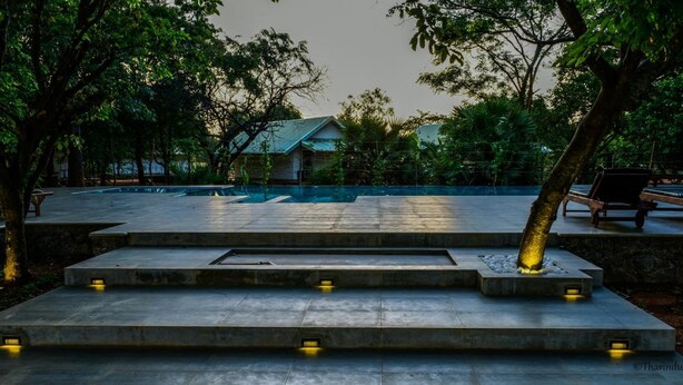A pool area with steps leading down to the water, surrounded by trees and benches. - Rangiri Dambulla Resort (Dambulla)