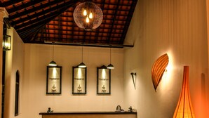 A reception area with a reception desk, three pendant lights, and a wall-mounted sculpture. - Rangiri Dambulla Resort (Dambulla)