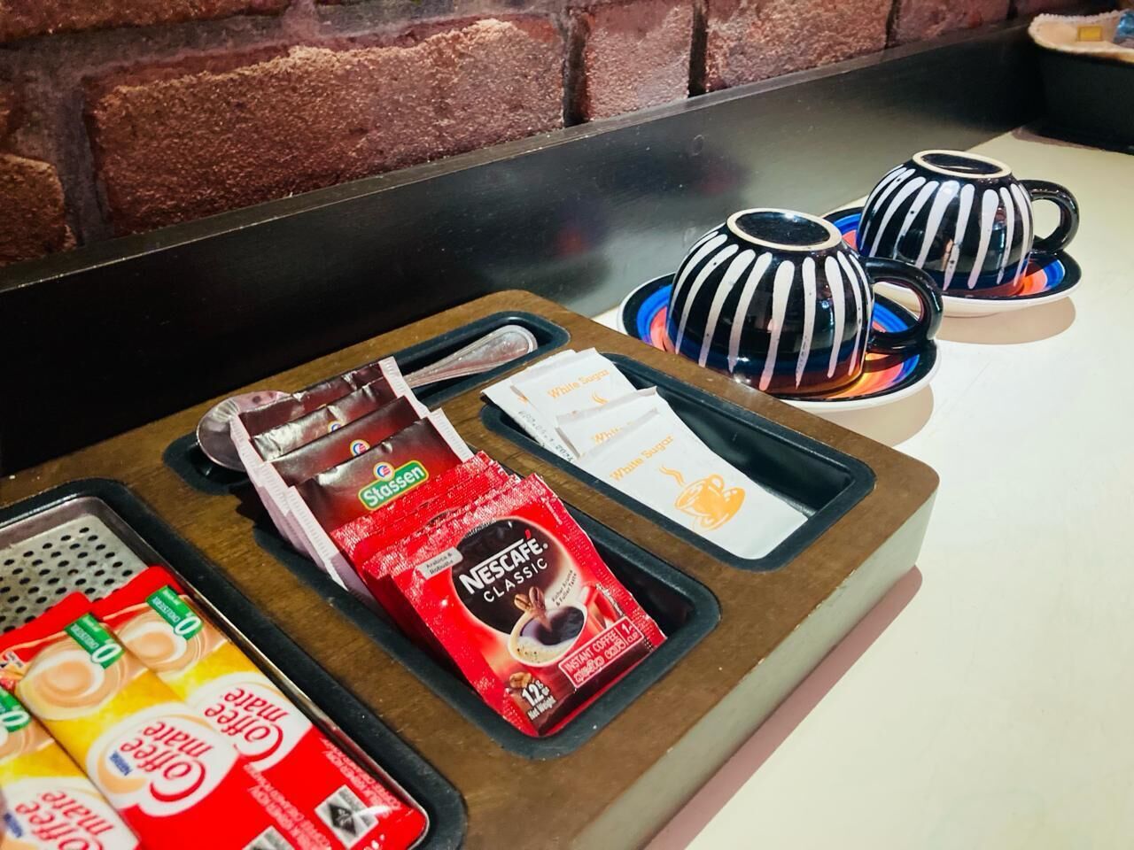 Een koffiehoek met diverse koffiekapsules en een schaal wegwerpbekers.
