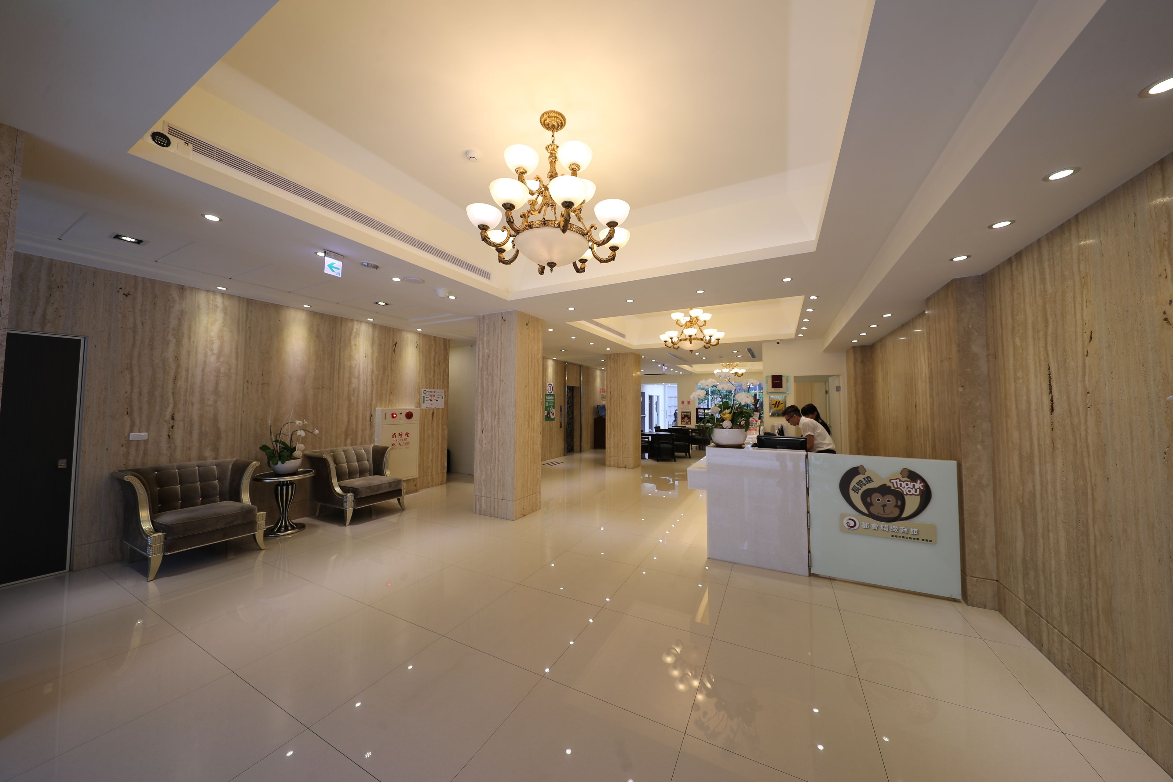 A spacious lobby with a reception desk, plush seating, and a chandelier.