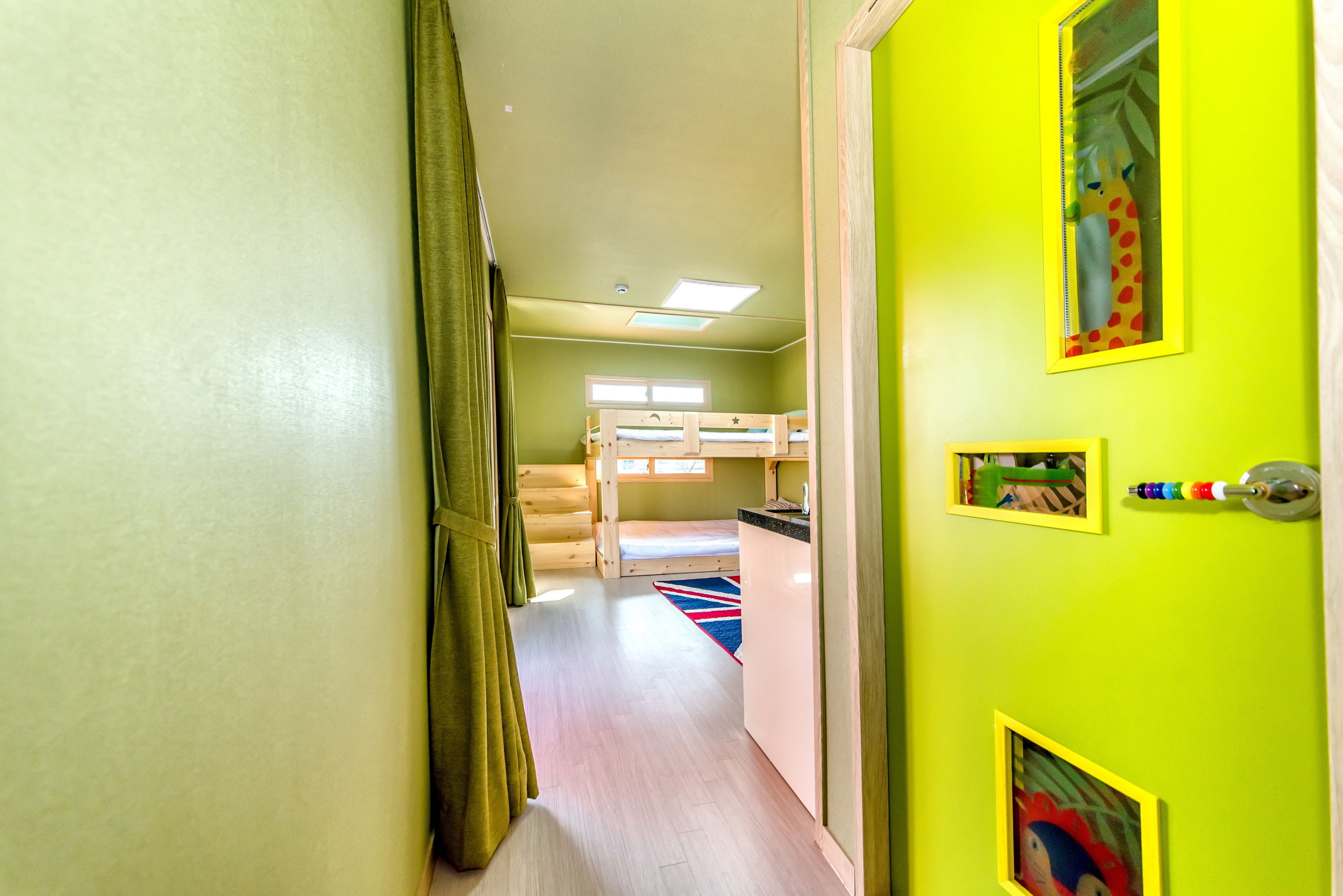 A room with bunk beds, a window, and a door with a mirror and picture frames.