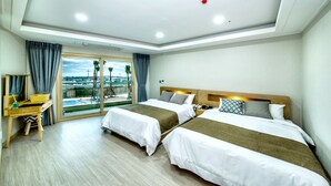 Ein Hotelzimmer mit zwei Betten, einem Schreibtisch und Blick auf die Stadt.