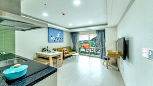 Eine moderne Küche mit einer blauen Schüssel auf der Arbeitsplatte, einem Essbereich mit Tisch und Stühlen, einer Couch und einem an der Wand befestigten Fernseher.