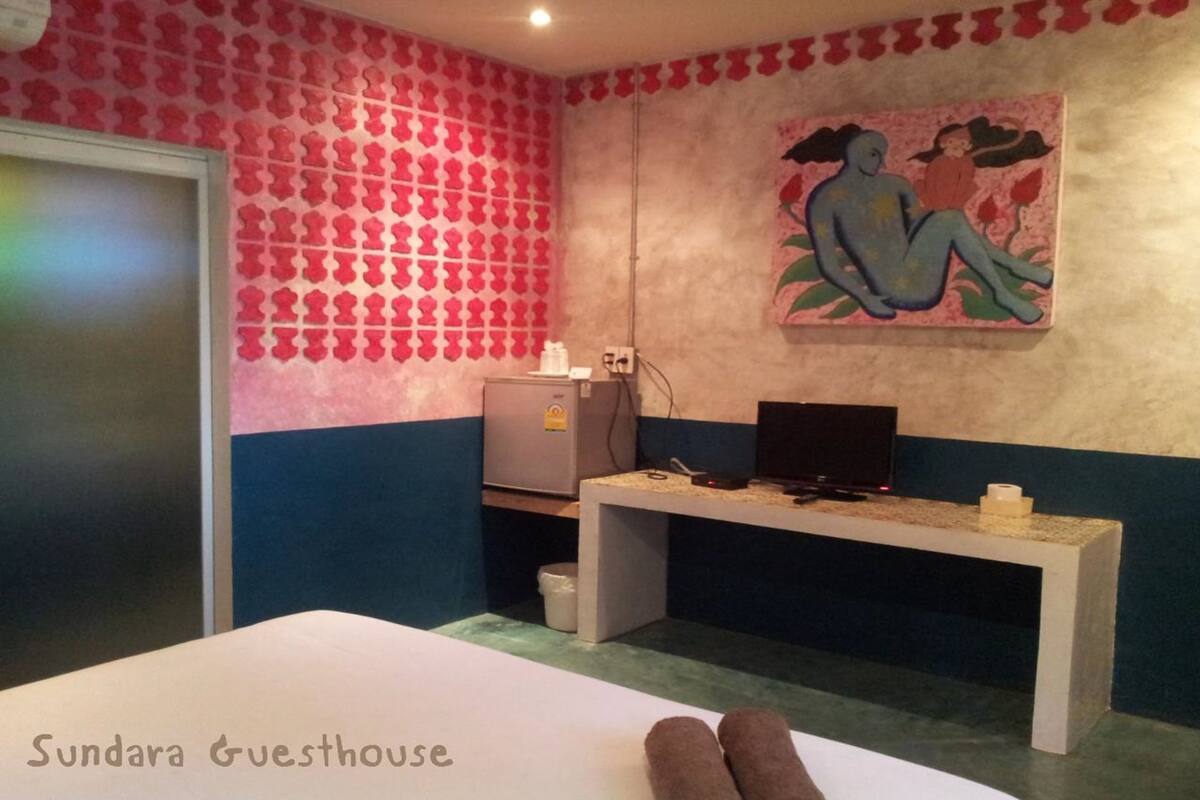 Una habitación con una cama, un escritorio, un televisor y un cuadro en la pared.