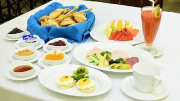 A table set with various dishes including bread, fruits, eggs, and a drink.