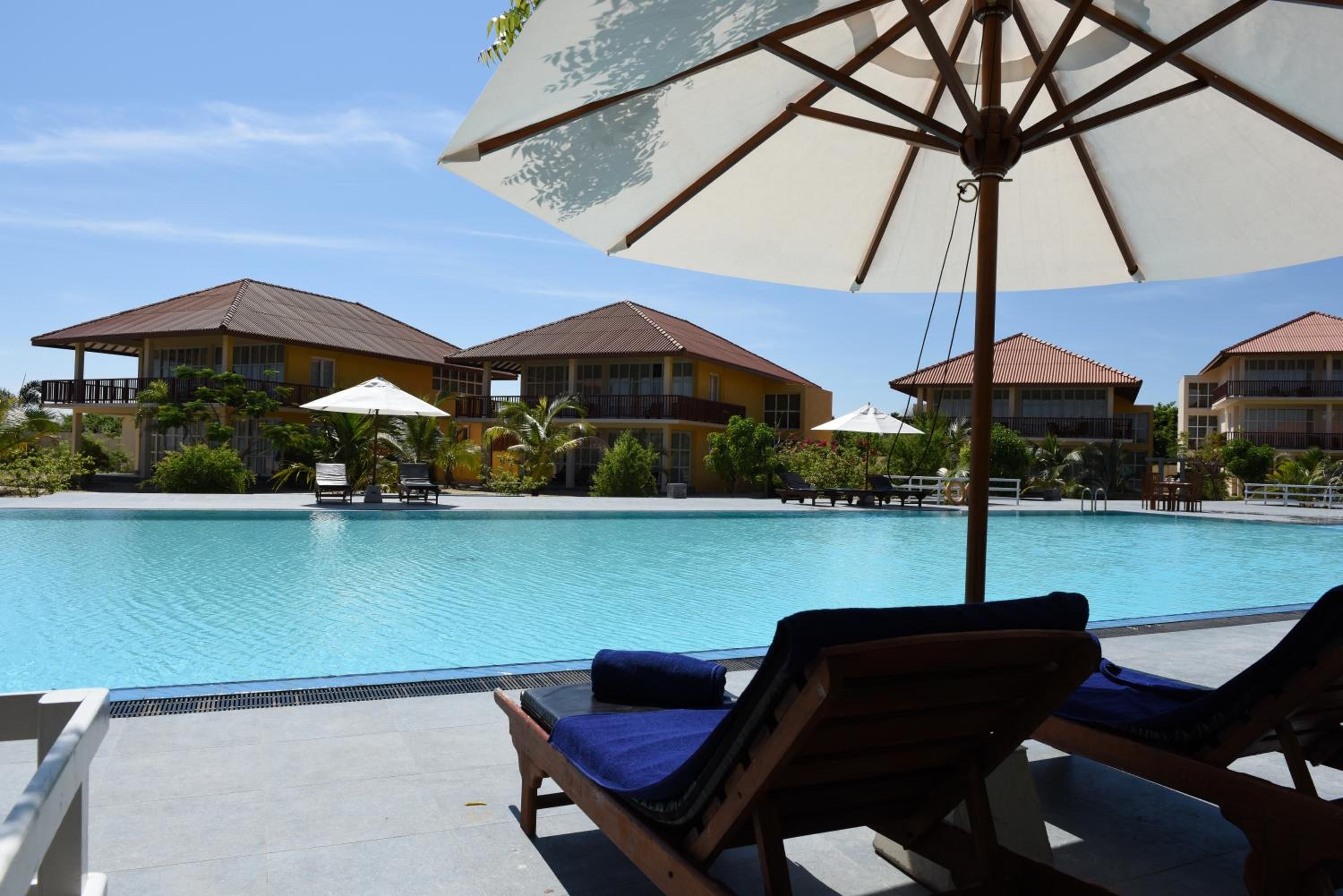 A pool area with lounge chairs and umbrellas, surrounded by buildings with balconies.