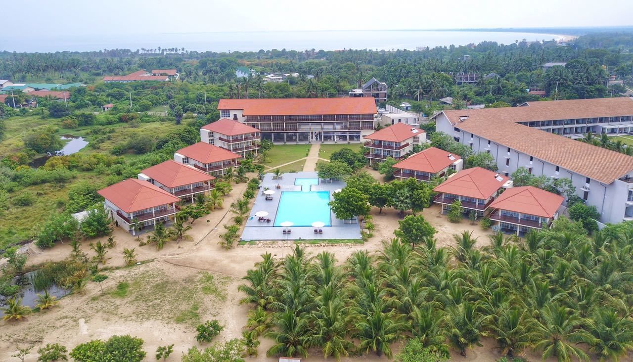 A resort with multiple buildings, a central pool, and surrounding palm trees.