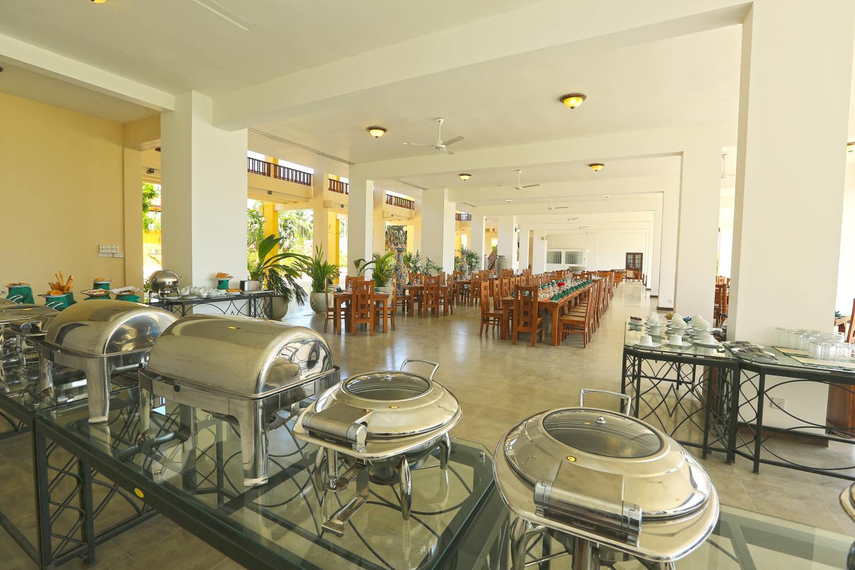 A spacious dining area with multiple tables and chairs, buffet stations with food service equipment, and a bright, well-lit interior.