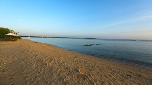 A beach with a clear sky, calm water, and a small structure on the left. - Passi Villas Passikudah (Pasikuda)