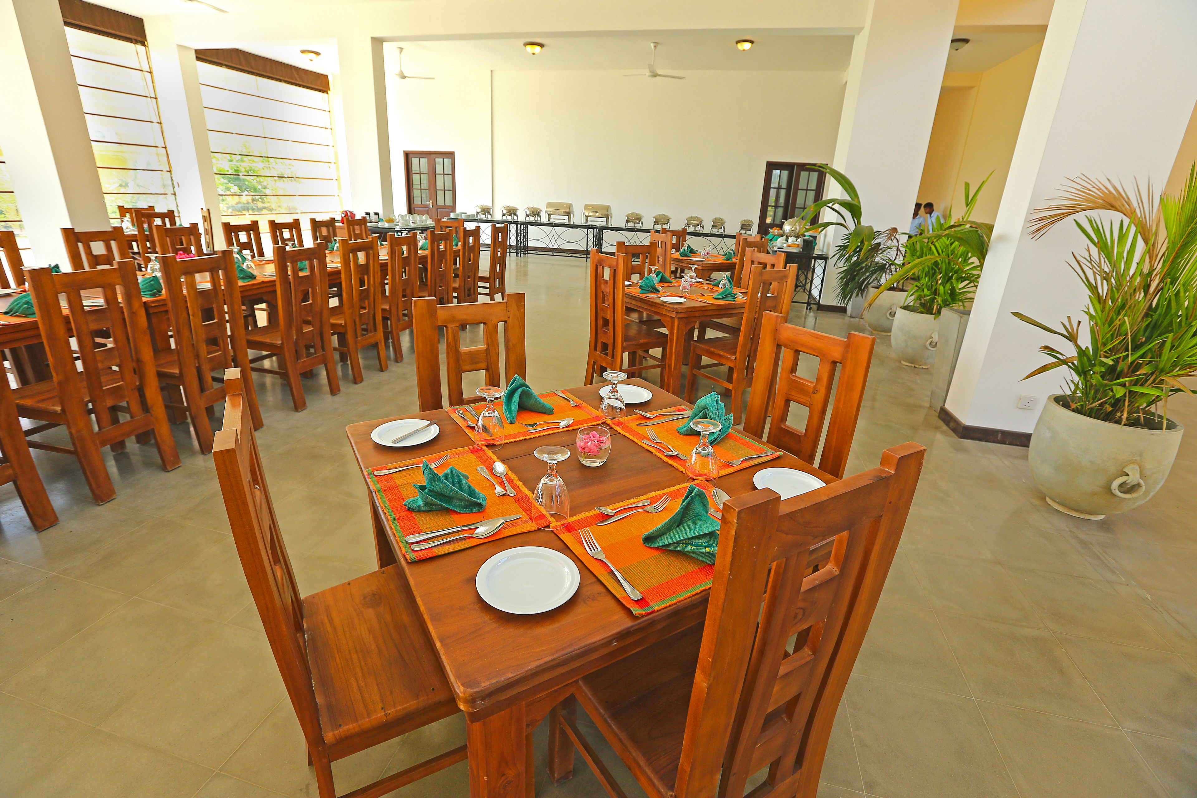 A dining area with multiple wooden tables and chairs, arranged in rows.