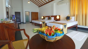 A hotel room with two beds, a dining area, and a fruit basket on a table. - Passi Villas Passikudah (Pasikuda)