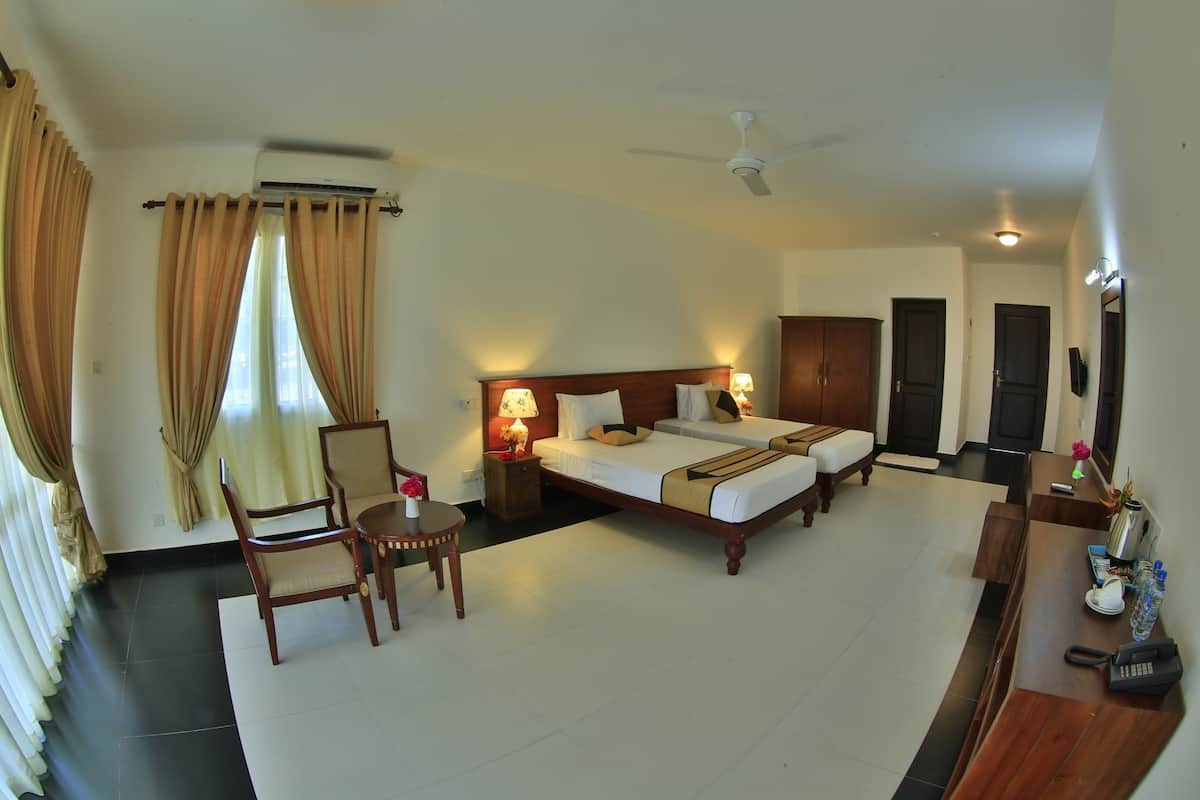 A hotel room with a bed, a desk, a chair, an air conditioner, and a ceiling fan.