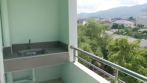 A balcony with a sink and a view of a residential area with trees and buildings. - C.S. Apartment Hat Yai (Hat Yai)