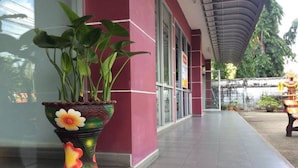 A potted plant with a colorful design in front of a building with a curved roof and a tiled floor. - C.S. Apartment Hat Yai (Hat Yai)