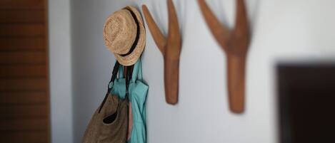 A wall with a hat, a pair of gloves, and a brown bag hanging on hooks.