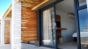 A modern hotel room with a sliding glass door, wooden slats on the exterior wall, and a visible bed and seating area inside. - Windtown Lagoon Hotel (Langebaan)