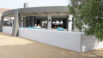 Een terras buiten met een modern ontwerp, met een witte muur en blauwe kussens.