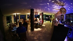 A modern restaurant with a bar area, featuring a unique ceiling design and ambient lighting. - Windtown Lagoon Hotel (Langebaan)