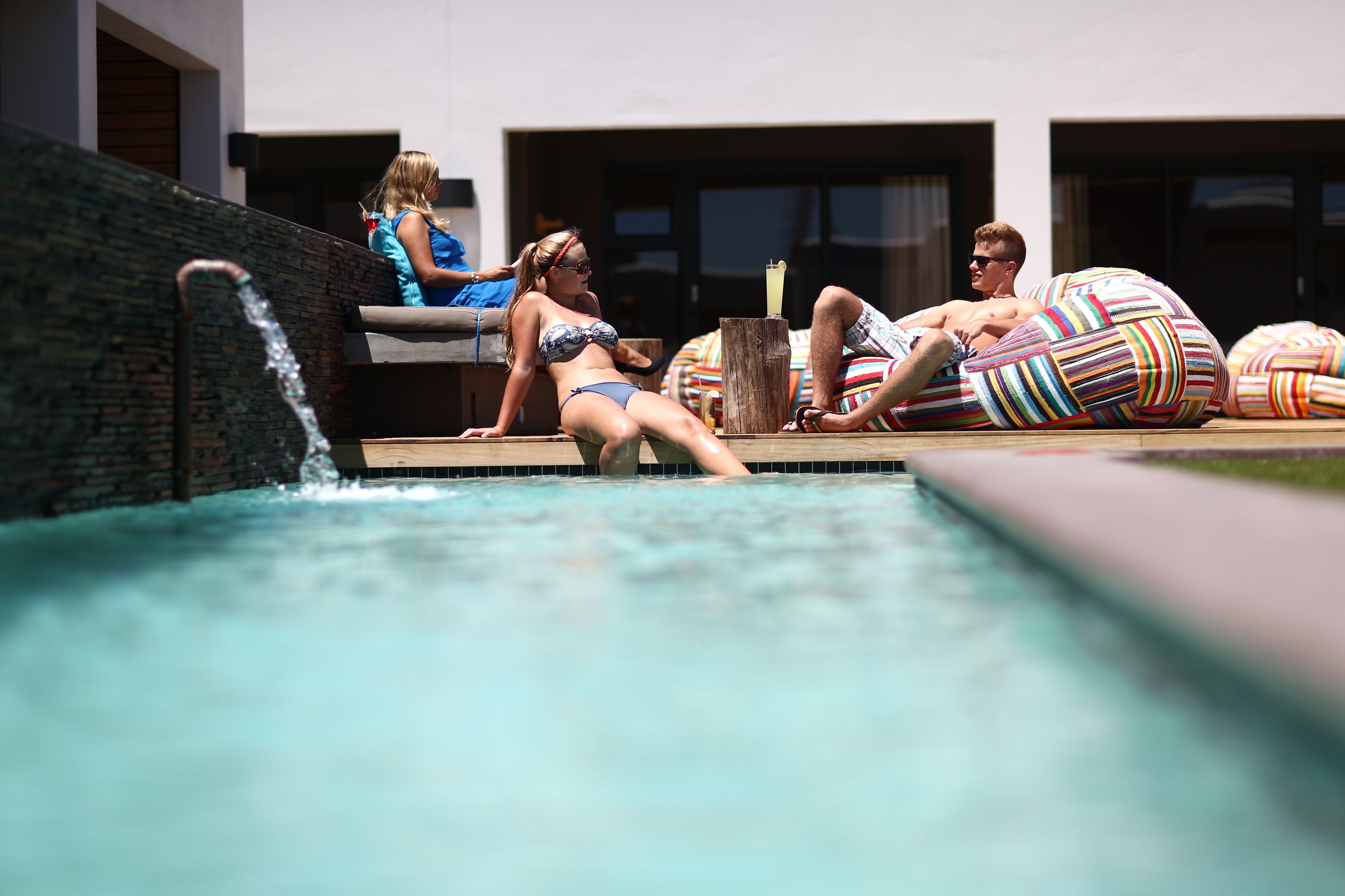 Een zwembad met ligbedden en een persoon in een bikini.