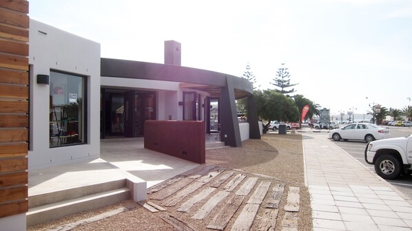 A modern building with a glass storefront, a wooden facade, and a gravel pathway leading to the entrance. - Windtown Lagoon Hotel (Langebaan)