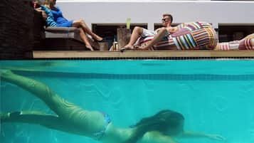 A poolside area with a clear view of the pool, lounge chairs, and a person swimming.
