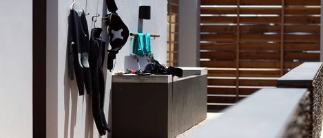 A modern outdoor area with a concrete planter, a wall-mounted coat rack, and a wooden fence.