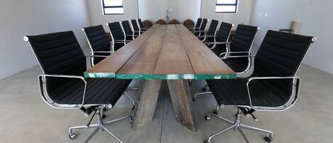 Une salle de conférence avec une longue table en bois et des chaises de bureau noires.