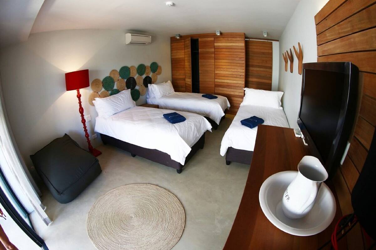 Ein Hotelzimmer mit zwei Betten, einem Fernseher, einem Holzschrank, einer roten Lampe und einem Teppich.