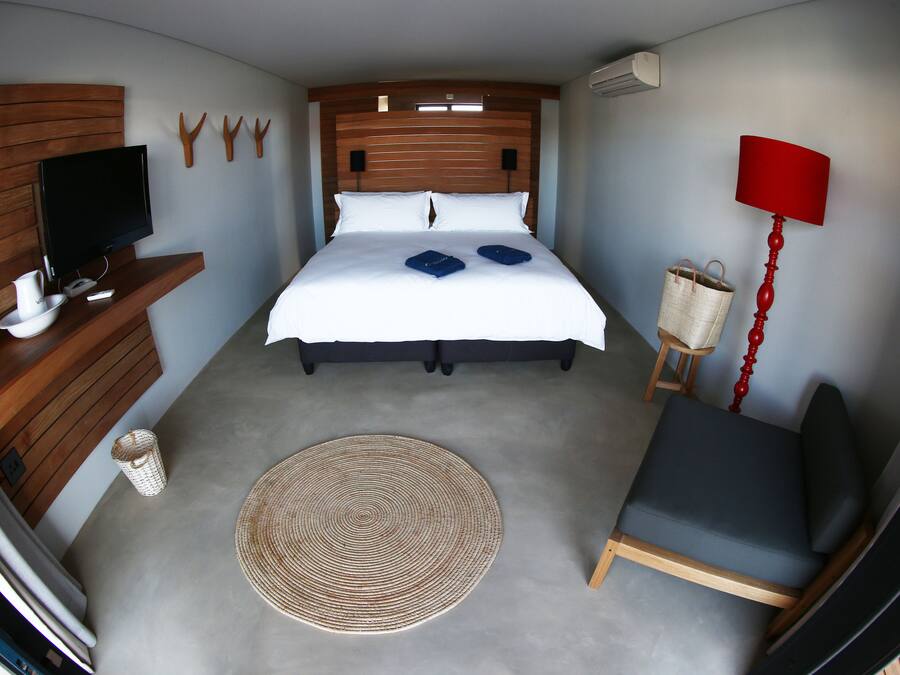 Een slaapkamer met een bed, een televisie, een stoel, een lamp en een klein tafeltje.