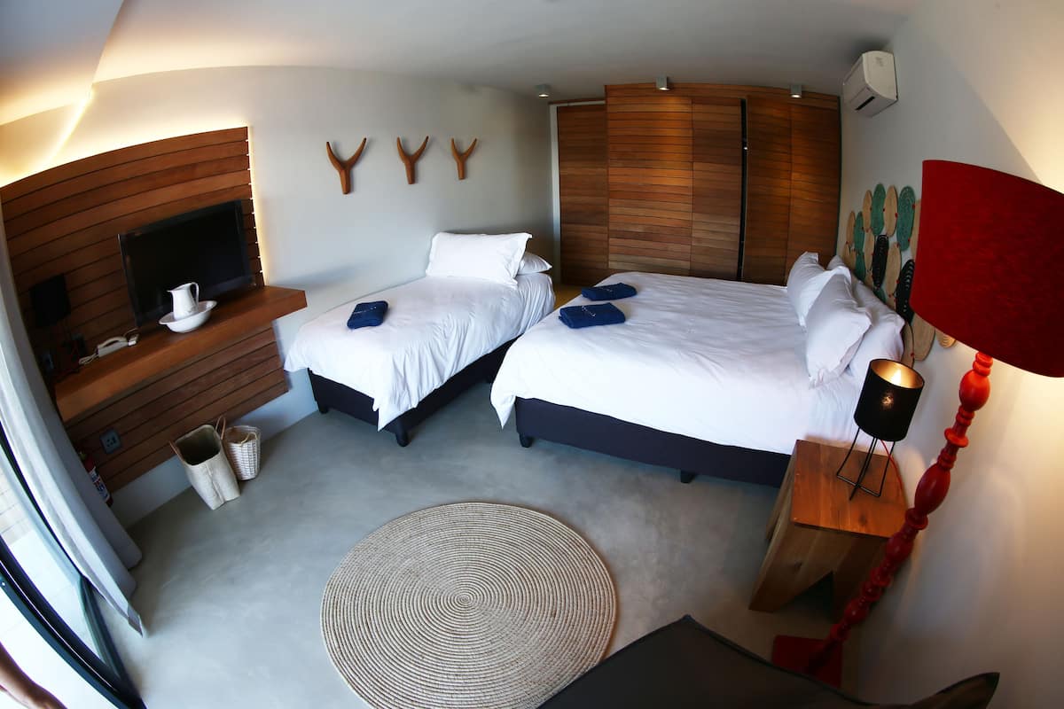Ein Hotelzimmer mit zwei Betten, einem Fernseher, einem Holzschrank, einer roten Lampe und einer Wandklimaanlage.