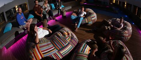 A rooftop lounge area with multiple bean bags and seating options, a pool, and a modern architectural design.