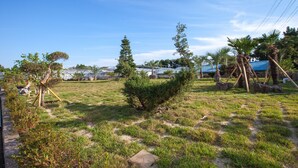 A grassy outdoor area with trees and a clear sky. - Fellisia Hotel (Seogwipo)