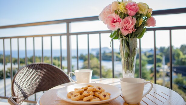 A balcony with a table set for breakfast, including pastries and a vase of flowers. - Fellisia Hotel (Seogwipo)
