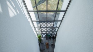 A view from a window looking down a narrow corridor with a checkered floor, a seating area with a table and chairs, and a potted plant. - Fellisia Hotel (Seogwipo)
