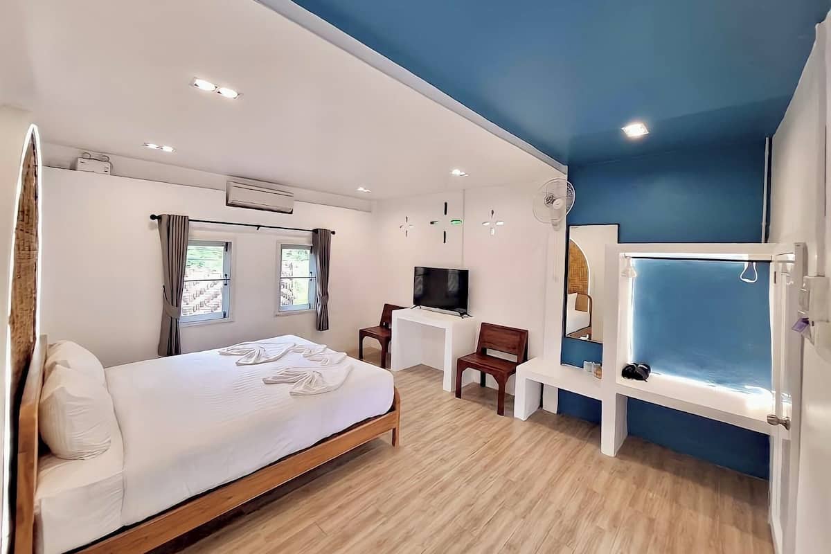 A modern hotel room with a bed, desk, chair, TV, and a window with a view.