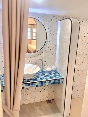 Een badkamer met een wit wastafelmeubel, een spiegel en een betegelde achterwand.