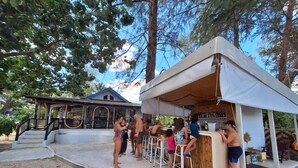 A beachside bar with a covered seating area, a staircase leading to a building, and a sandy foreground. - PAN Beachfront Resort Krabi (Krabi)