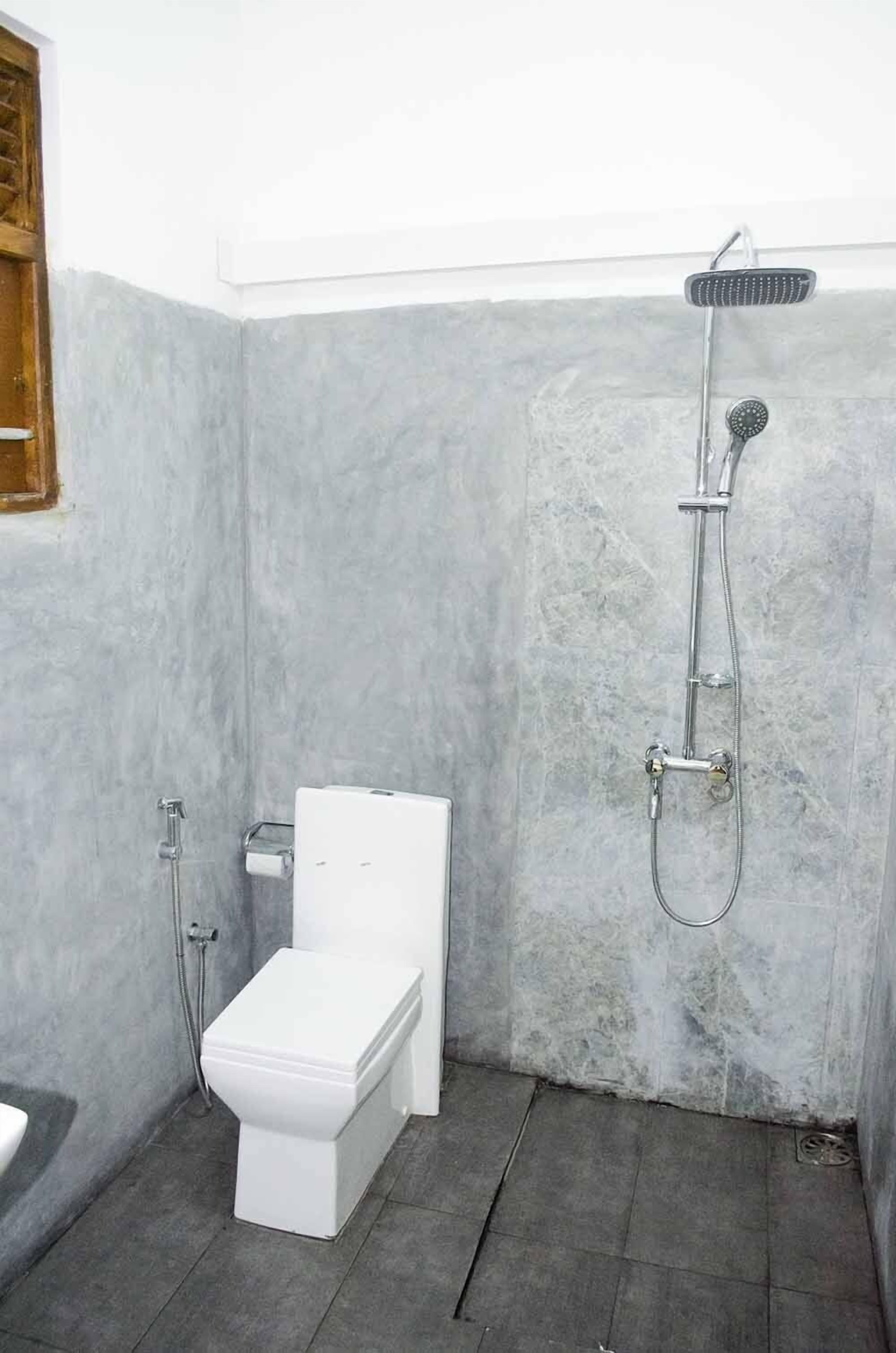 A bathroom with a white toilet, a shower with a handheld showerhead, and a towel rack.