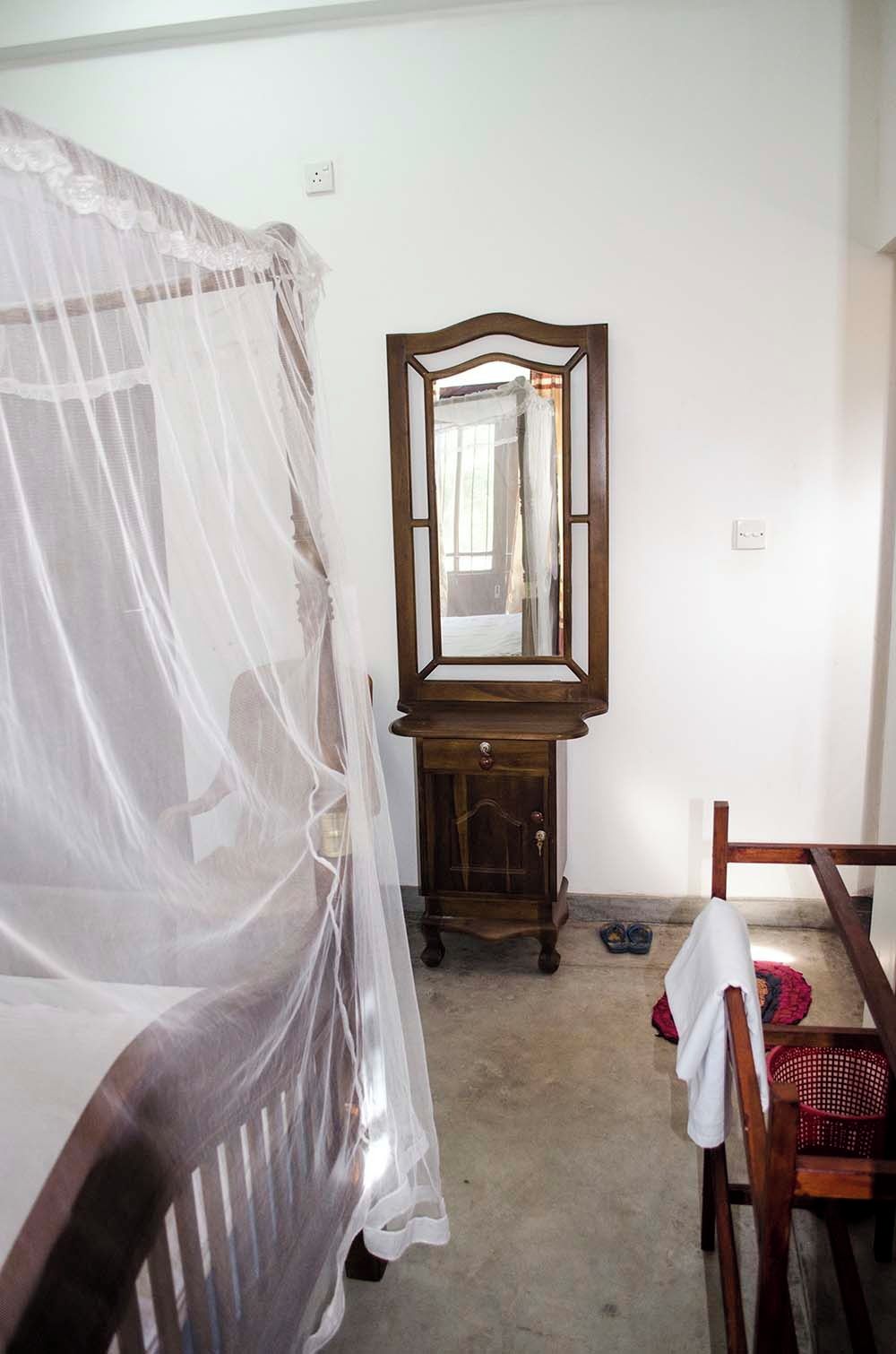 Une chambre à coucher avec un lit, une commode en bois, un miroir et une chaise.