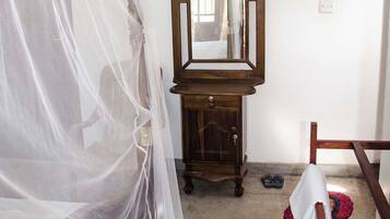 Une chambre à coucher avec un lit, une commode en bois, un miroir et une chaise.