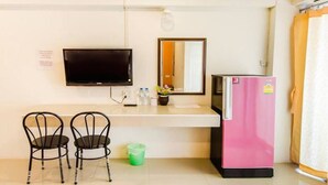 A small kitchenette with a pink refrigerator, a flat-screen TV mounted on the wall, a mirror, and two chairs. - W Apartment Hat Yai (Hat Yai)