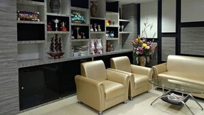 A modern living room with a sofa set, a glass coffee table, and a decorative shelf with various items. - W Apartment Hat Yai (Hat Yai)