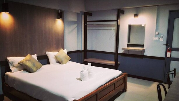 A hotel room with a large bed, bedside tables, a mirror, and a bench. - W Apartment Hat Yai (Hat Yai)