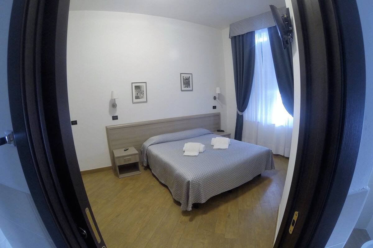 A bedroom with a bed, bedside tables, and a window with curtains.