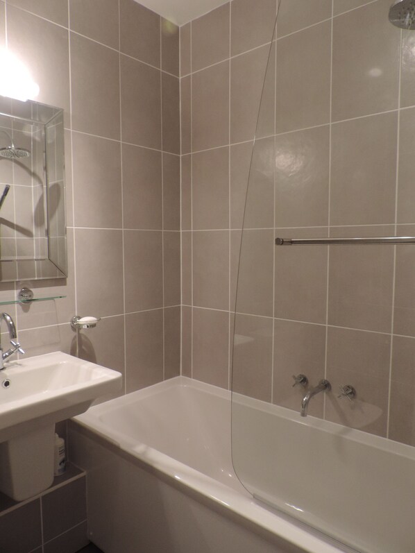 Un baño con bañera, lavamanos y cabina de ducha de vidrio.