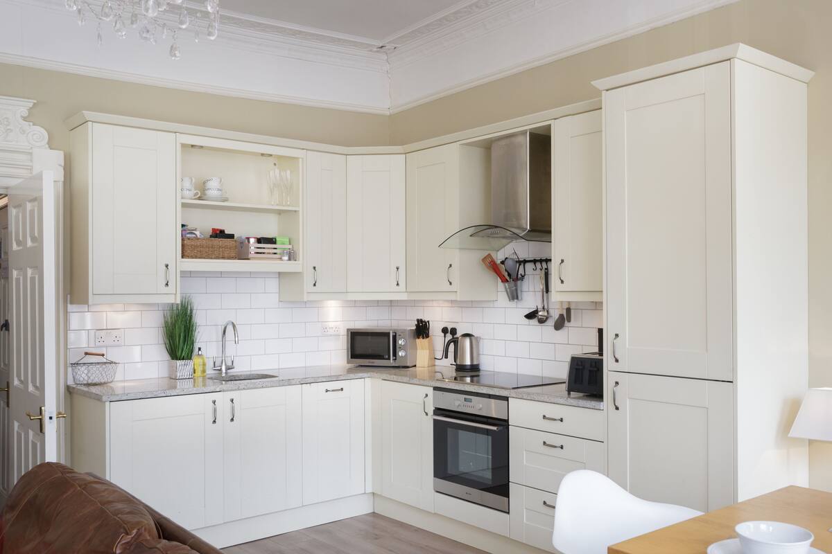 A modern kitchen with white cabinetry, a built-in oven, and a microwave.