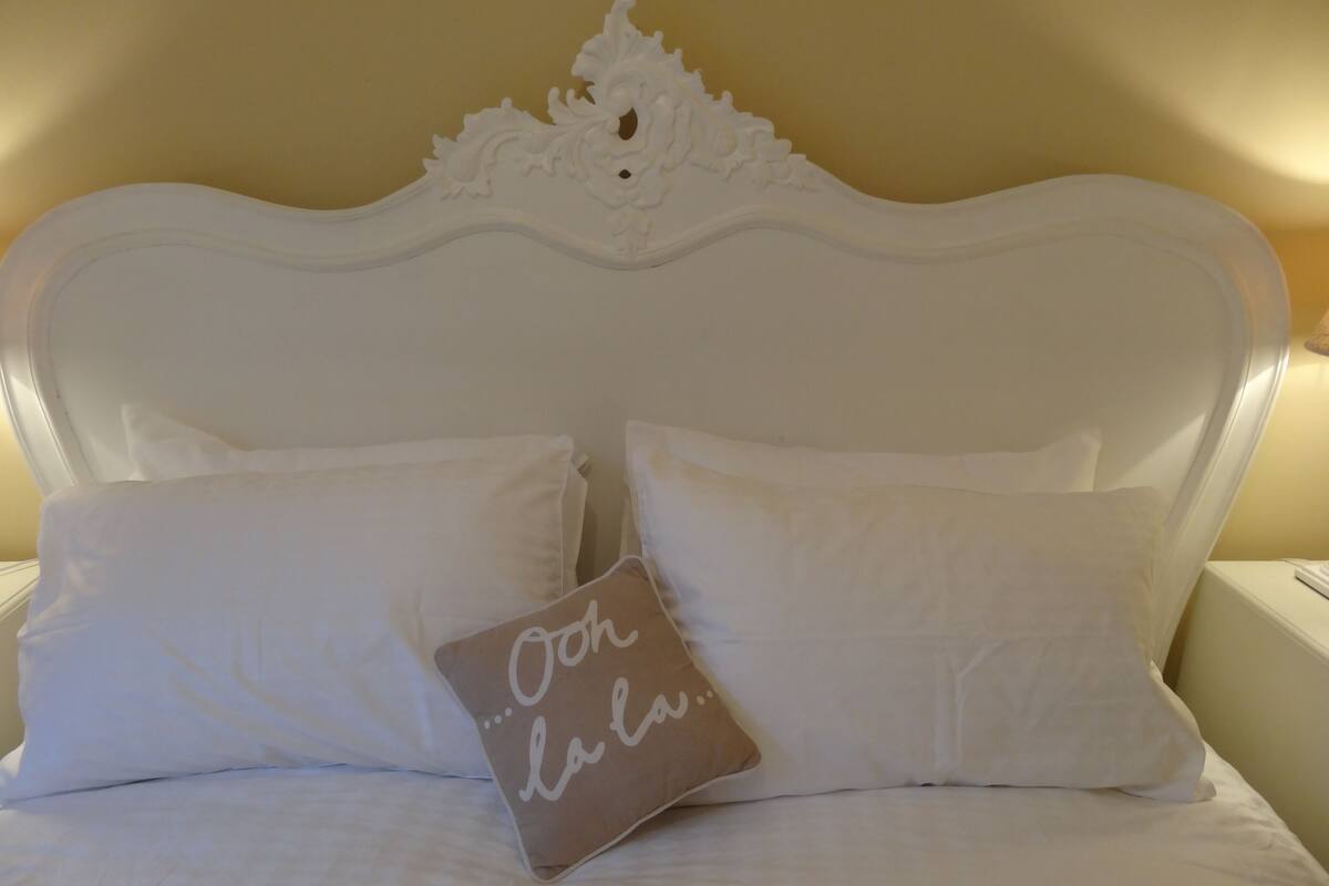 A bed with white bedding and two pillows, one with a message.