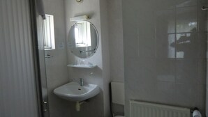 Un baño pequeño y funcional con un lavamanos blanco, un espejo encima y un inodoro.