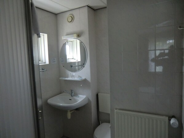 A small, compact bathroom with a white sink, a mirror above it, and a toilet. - Hotel Bergen (Bergen)