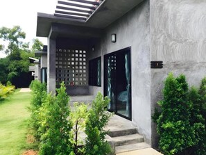 A modern building with a concrete facade, a set of steps leading to a door, and a small garden area with shrubs. - Baanwaan Resort Hat Yai (Hat Yai)